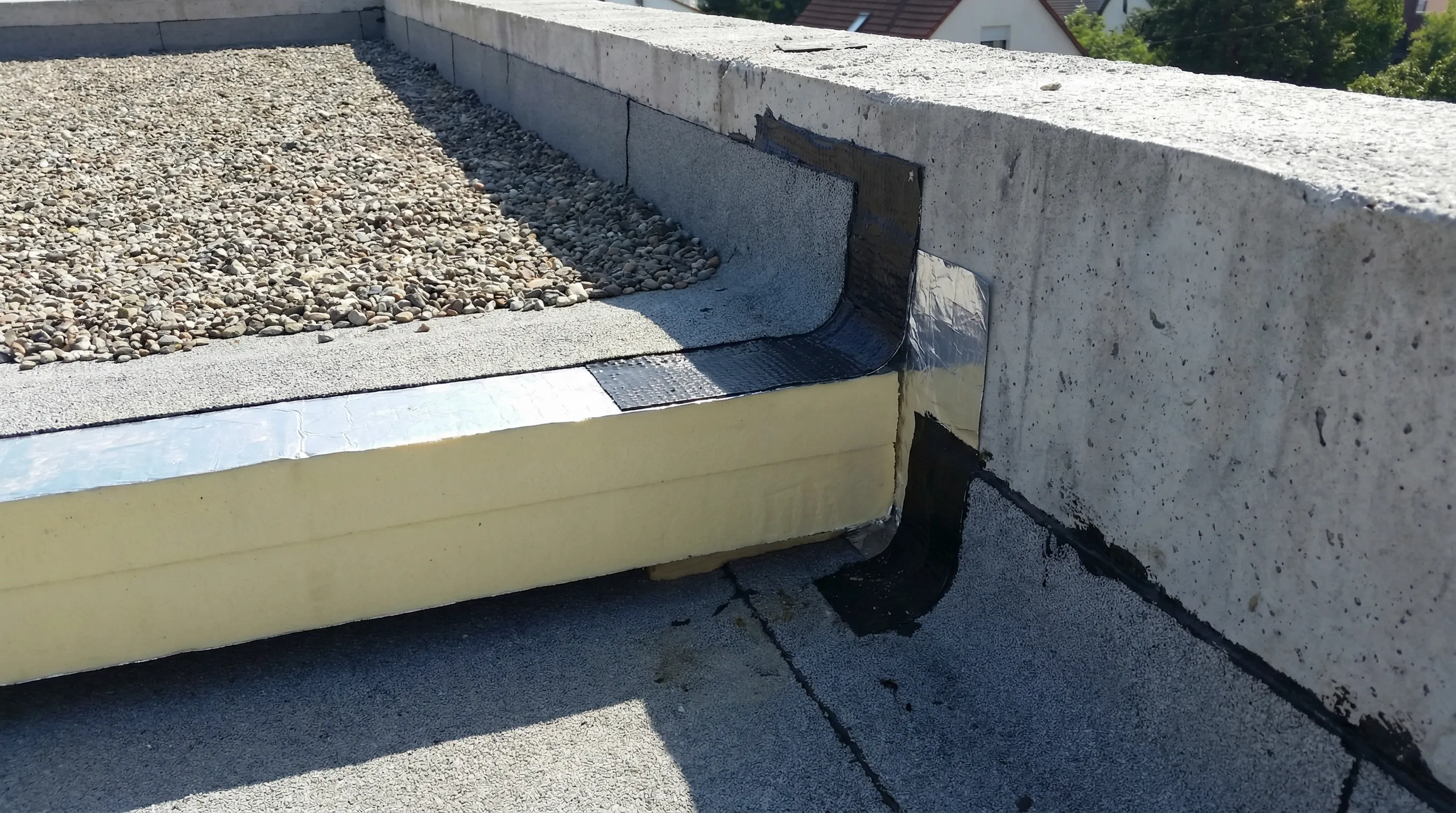 Montaż izolacji dachu płaskiego z żółtych płyt na stropodachu, uszczelnienie krawędzi przy murze