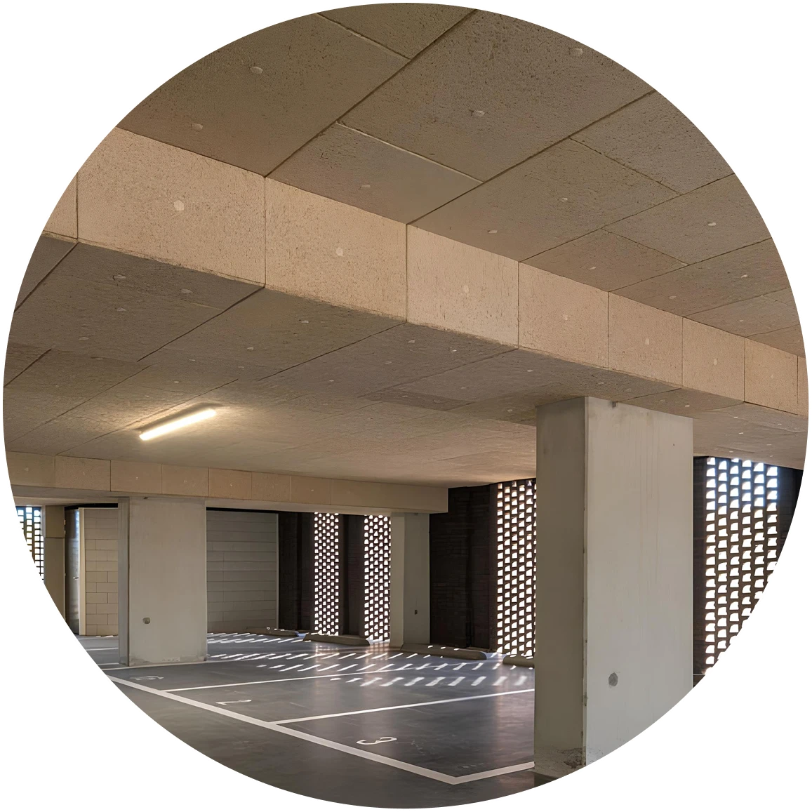 Pusta hala garażowa z betonowymi filarami i oznaczonymi miejscami parkingowymi