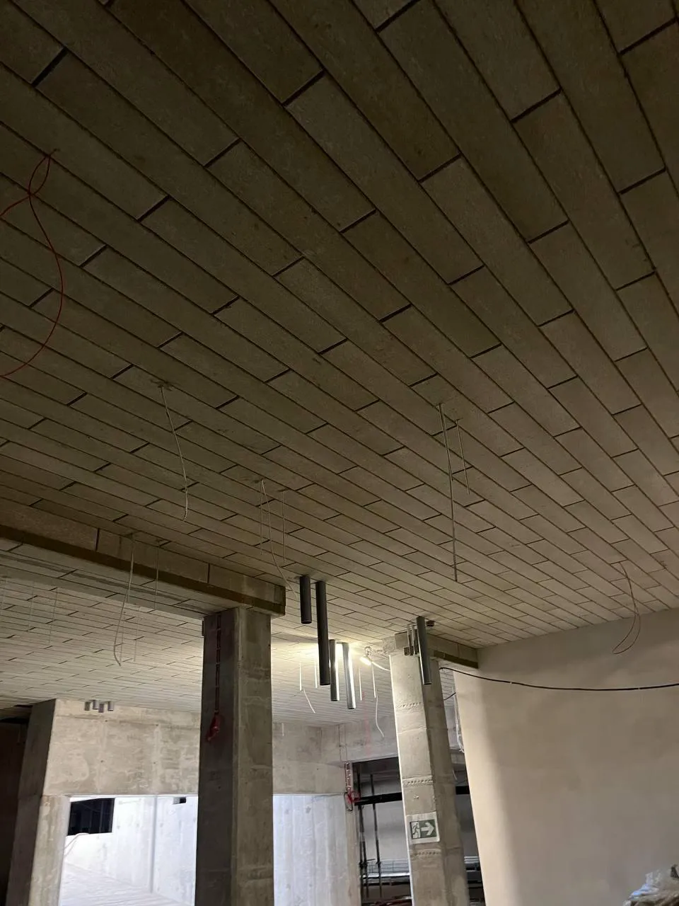 Ocieplenie stropu w surowym wnętrzu budynku z widocznymi przewodami i betonowymi słupami