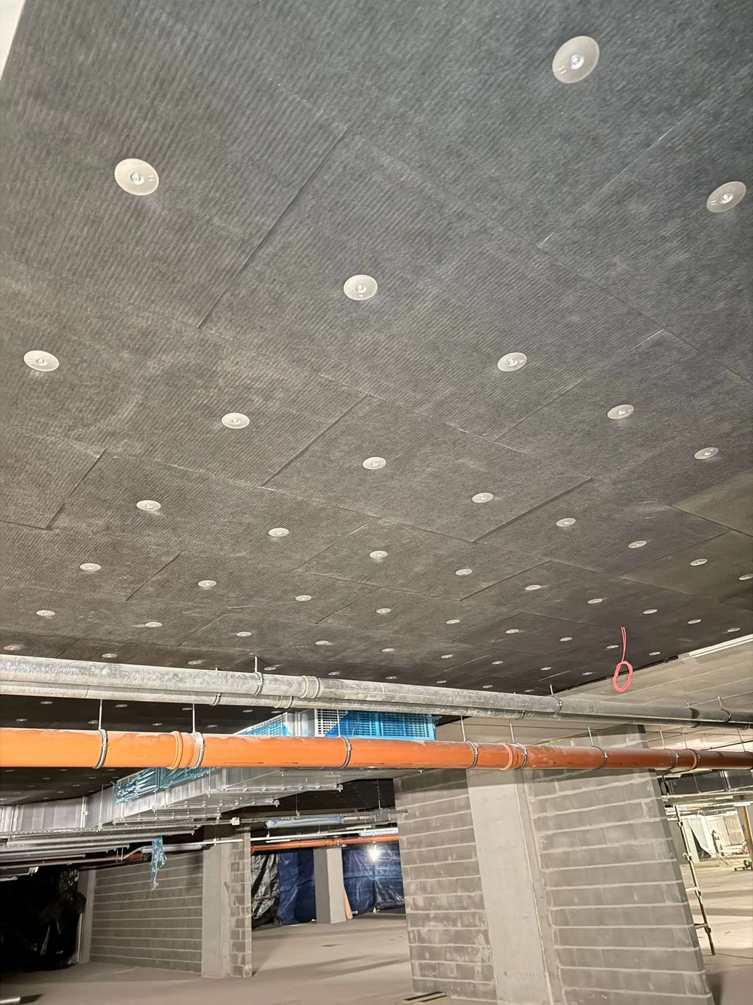 Ocieplenie stropu wełną mineralną montowaną plastikowymi talerzykami w budynku w trakcie prac