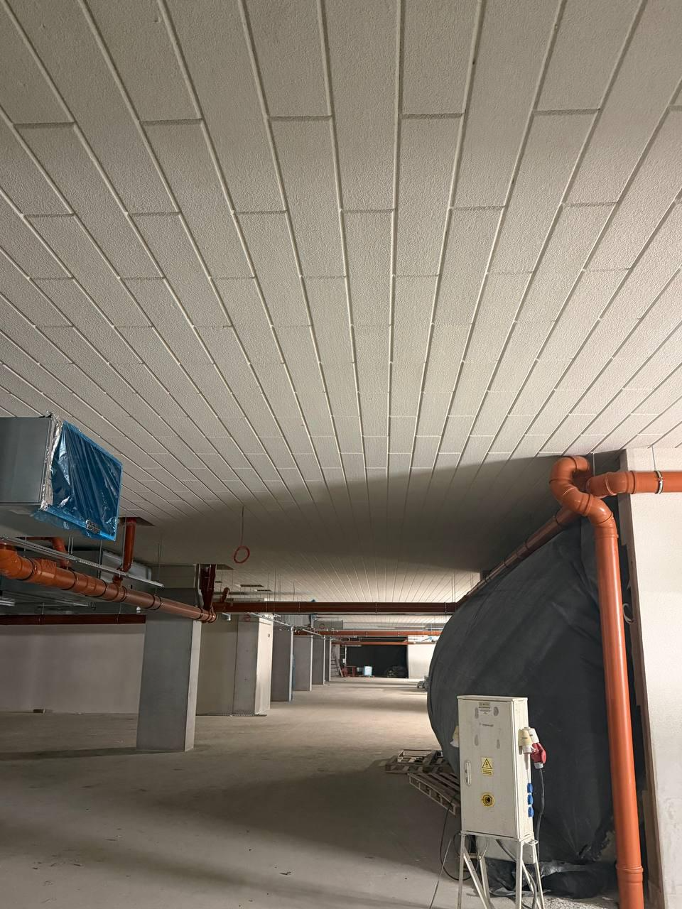 Wnętrze surowego budynku z instalacją przewodów wentylacyjnych i rur kanalizacyjnych pod sufitem