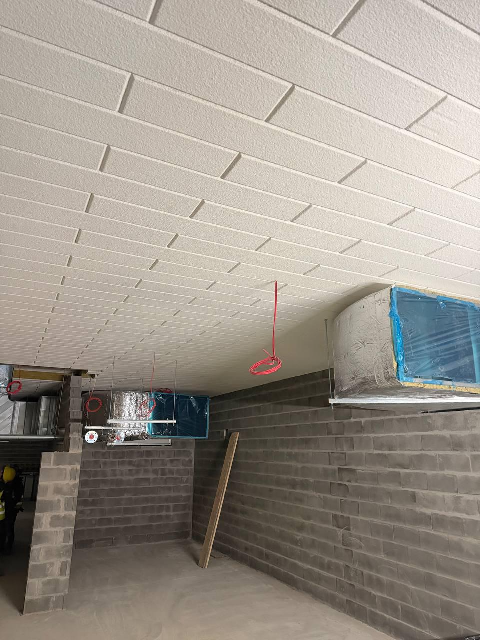 Podwieszony sufit z paneli i izolacją – Ocieplenie stropu z widocznymi kanałami wentylacyjnymi i przewodami elektrycznymi